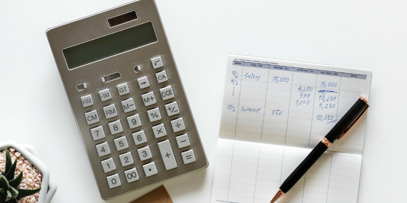 Someone working out their 2019 taxes with a calculator and pen and paper